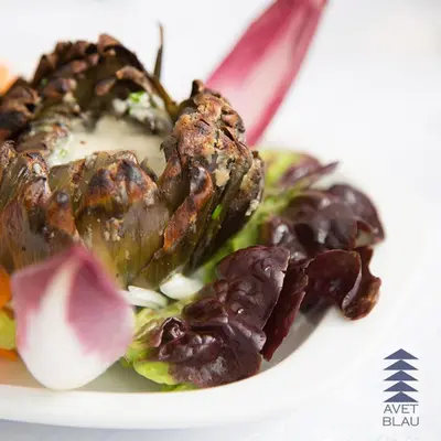 a plate of food with meat and vegetables on it at Hostal l'Avet Blau in Santa Fe de Montseny