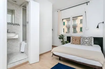 a white bedroom with a bed and a bathroom at Centric Apartments Paseo de Gracia in Barcelona