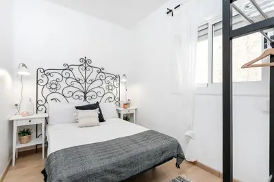 a white bedroom with a bed with a metal headboard at Centric Apartments Paseo de Gracia in Barcelona
