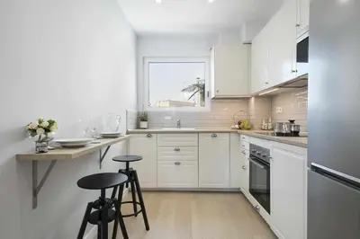 a white kitchen with white cabinets and stools in it at Apartment Leonor in Barcelona