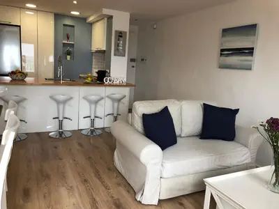 a living room with a white couch and a kitchen at Vilamarlux II in Vilassar de Mar