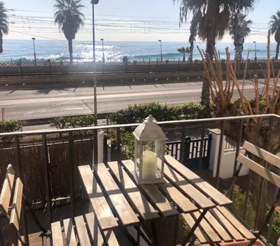 a wooden bench with a light on a railing with the beach at Vilamarlux II in Vilassar de Mar