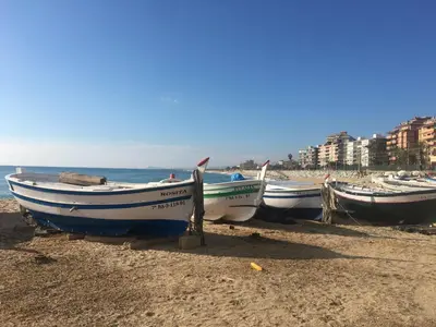 three boats sitting on the beach near the water at Vilamarlux II in Vilassar de Mar