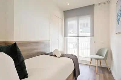 a bedroom with a bed and a chair and a window at Sitges Group Calm Beach in Sitges