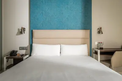 a bedroom with a white bed with a blue wall at Arya Stadium Hotel in Barcelona