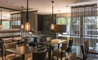 a restaurant with tables and chairs and windows at Hotel Actual in Barcelona