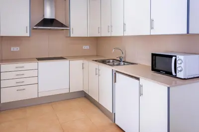 a kitchen with white cabinets and a sink and a microwave at Apartments Sorrabona in Pineda de Mar