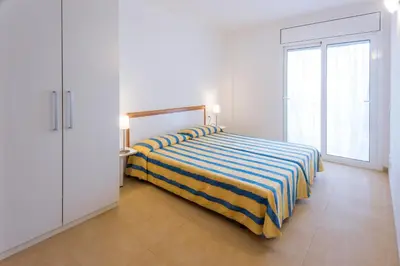 a bedroom with a bed with a striped blanket at Apartments Sorrabona in Pineda de Mar