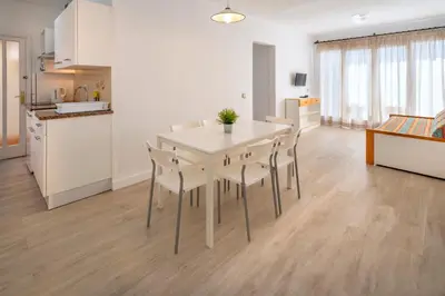 a kitchen and dining room with a white table and chairs at Apartments Sorrabona in Pineda de Mar