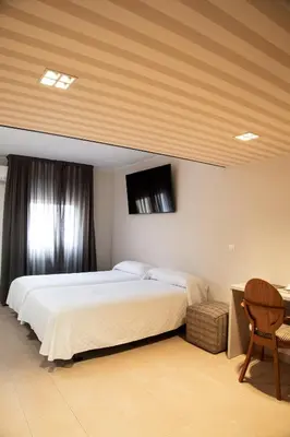 a bedroom with a bed and a tv on the wall at New Hotel Colon in Mataró
