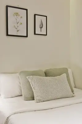 a white bed with two framed pictures on a white wall at Urban Chill Apartments by Olala Homes in Hospitalet de Llobregat