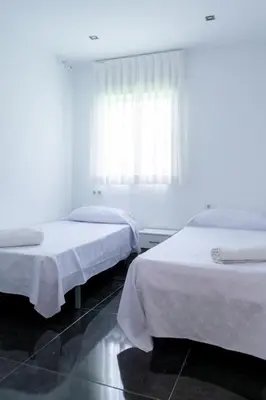 two beds in a white room with a window at Luxurious Villa Marly II piscina climatizada in Castelldefels