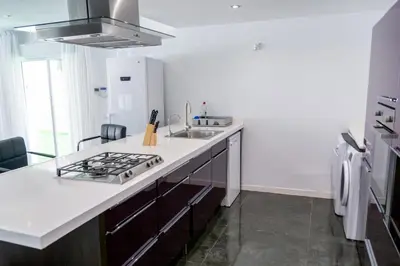 a white kitchen with a sink and a stove at Luxurious Villa Marly II piscina climatizada in Castelldefels