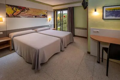 a hotel room with two beds and a table and a desk at Hotel Sabiote in Pineda de Mar