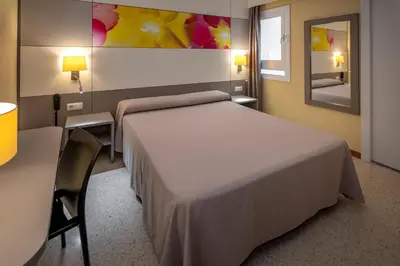 a bedroom with a bed and a table and chairs at Hotel Sabiote in Pineda de Mar
