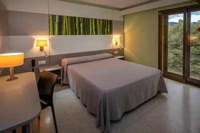 a bedroom with a bed and a table and a window at Hotel Sabiote in Pineda de Mar