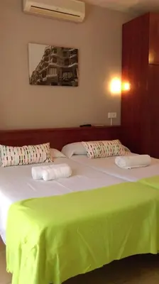 two beds in a room with a green blanket on them at Hostal Termes in Sitges