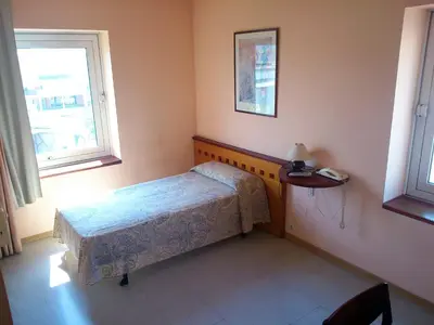 a small bedroom with a bed and a window at Hotel Montmeló in Montmeló
