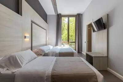 a hotel room with two beds and a flat screen tv at Plaza Goya Rooms in Barcelona