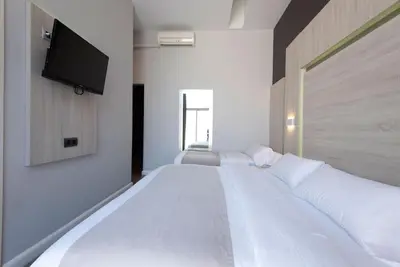 a bedroom with three beds with a flat screen tv on the wall at Plaza Goya Rooms in Barcelona