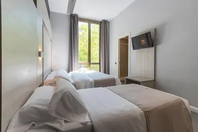 a hotel room with three beds and a television at Plaza Goya Rooms in Barcelona