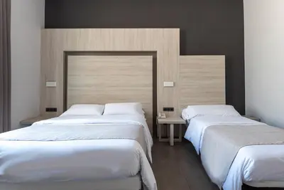 two beds in a hotel room with white sheets at Plaza Goya Rooms in Barcelona