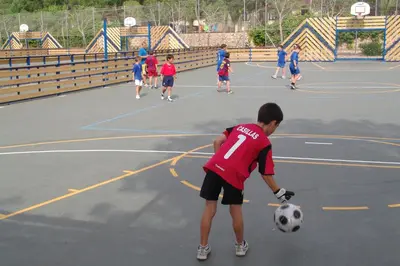 a young boy playing with a soccer ball on a court at Camping Vilanova Park in Vilanova i la Geltrú