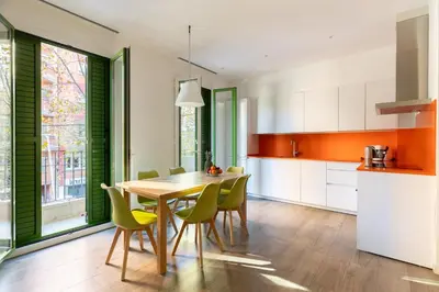 a kitchen with a wooden table and green chairs at Cosmo Apartments Marina – Auditori in Barcelona