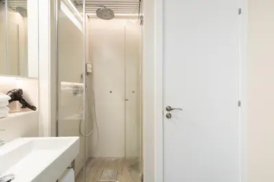 a white bathroom with a shower and a sink at Cosmo Apartments Marina – Auditori in Barcelona
