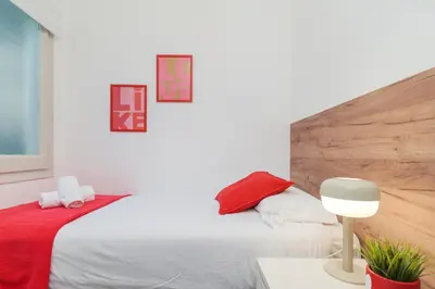 a bedroom with a white bed and a red blanket at Spacious 4 Bedroom Apartment Fira BCN & Camp Nou in Barcelona