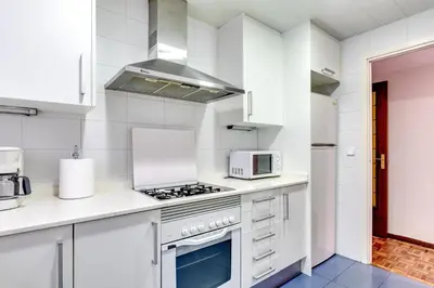 a white kitchen with a stove and a microwave at Spacious 4 Bedroom Apartment Fira BCN & Camp Nou in Barcelona
