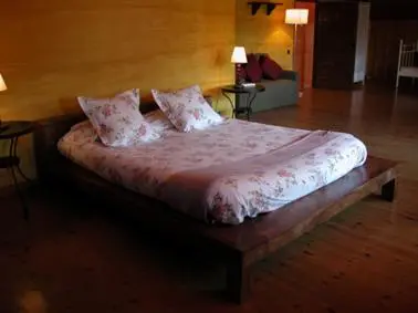 a large bed in a room with a wooden floor at Masia Vista Hermosa in Vallromanas