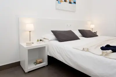 a bedroom with a white bed with a night stand at 08028 Apartments in Barcelona