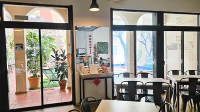 a dining room with tables and chairs and windows at Ten To Go Hostel in Barcelona