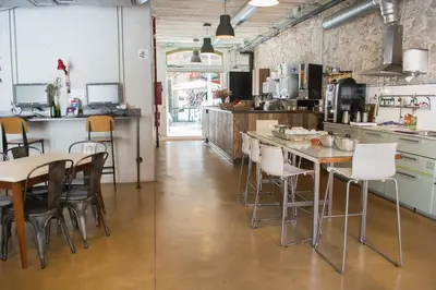 a kitchen with white chairs and tables in a room at Ten To Go Hostel in Barcelona