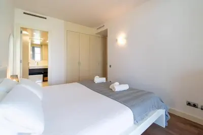 a bedroom with a large white bed and a bathroom at Unique Rentals-Seafront Luxe Suites in Barcelona