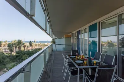 a balcony with a table and chairs and the ocean at Unique Rentals-Seafront Luxe Suites in Barcelona