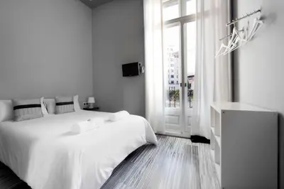 a white bedroom with a white bed and a window at Hostal Boutique Khronos in Barcelona