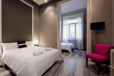 a bedroom with a large white bed and a pink chair at Hostal Boutique Khronos in Barcelona
