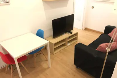 a living room with a television and a table and chairs at NEW! Cute apartment near metro in Barcelona