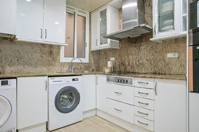 a kitchen with white cabinets and a washer and dryer at Alcam Calabria in Barcelona