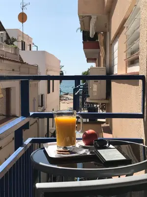 a glass of orange juice sitting on a table on a balcony at Sunny Flat in Sitges 30 Seconds to Beach, Balcony & Sea Views! in Sitges