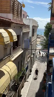 a person walking down a street next to a beach at Sunny Flat in Sitges 30 Seconds to Beach, Balcony & Sea Views! in Sitges