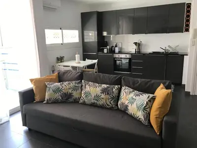 a living room with a couch and a kitchen at Sunny Flat in Sitges 30 Seconds to Beach, Balcony & Sea Views! in Sitges