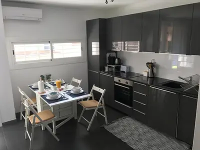 a kitchen with black cabinets and a table and chairs at Sunny Flat in Sitges 30 Seconds to Beach, Balcony & Sea Views! in Sitges