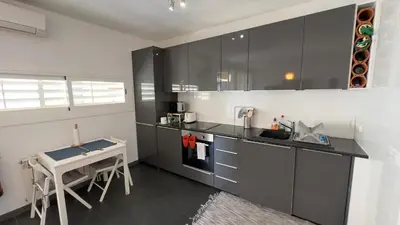 a kitchen with black and white cabinets and a table at Sunny Flat in Sitges 30 Seconds to Beach, Balcony & Sea Views! in Sitges