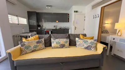 a couch with pillows sitting in a living room at Sunny Flat in Sitges 30 Seconds to Beach, Balcony & Sea Views! in Sitges