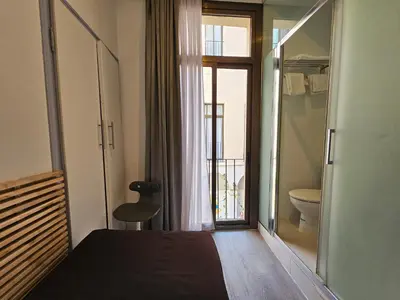 a bedroom with a bed and a bathroom with a toilet at Hotel Palermo in Barcelona