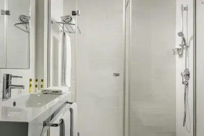 a white bathroom with a shower and a sink at Ikonik Lex in Hospitalet de Llobregat