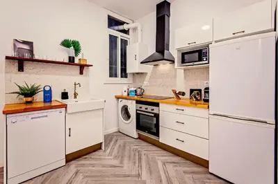 a kitchen with white appliances and a wooden floor at Sweett - Urgell in Barcelona